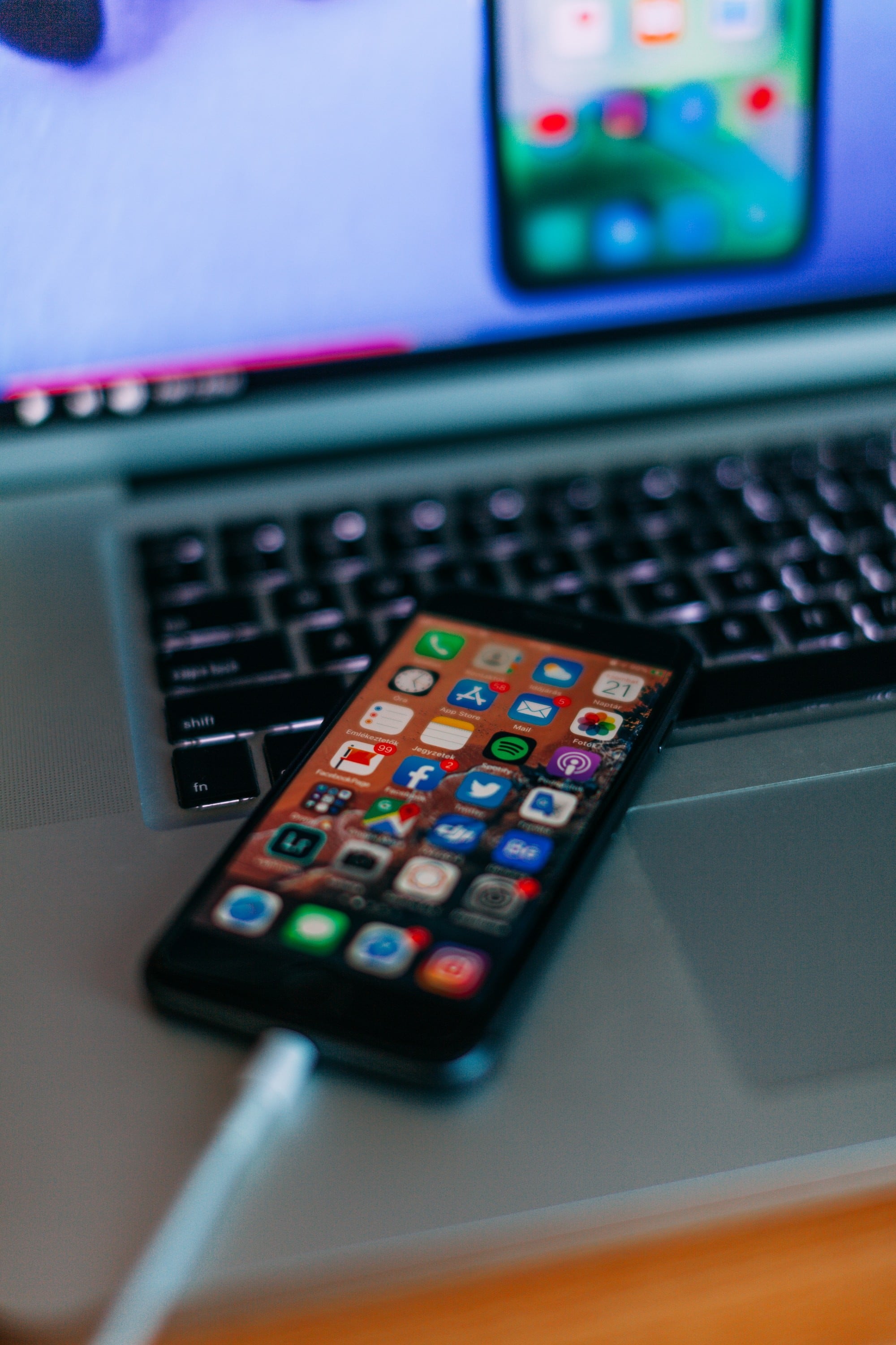 Cellphone screen with a full display of icons for different apps and a computer keyboard is in the background